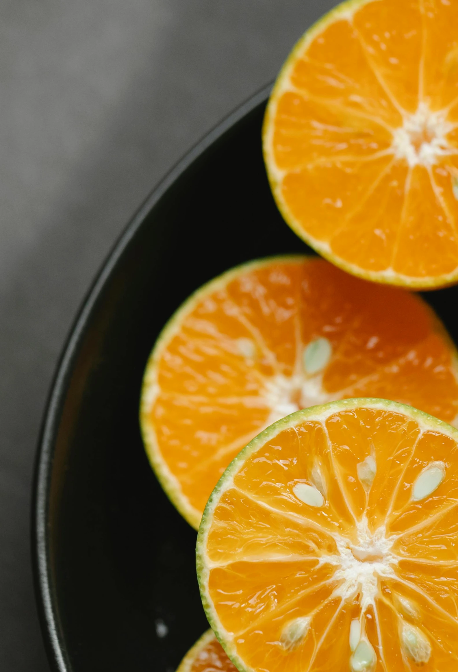 a black plate topped with sliced oranges on top of a table, by Carey Morris, trending on unsplash, lime, orange metal ears, closeup headshot, soup