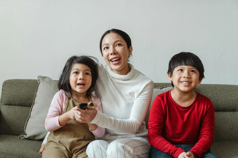 a woman and two children sitting on a couch, a cartoon, pexels contest winner, incoherents, an asian woman, netflix series, youtube thumbnail, kids playing