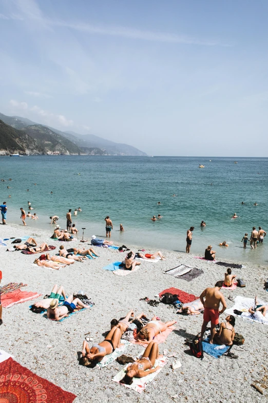 a group of people laying on top of a sandy beach, cinq terre, people swimming, sweltering heat, flatlay