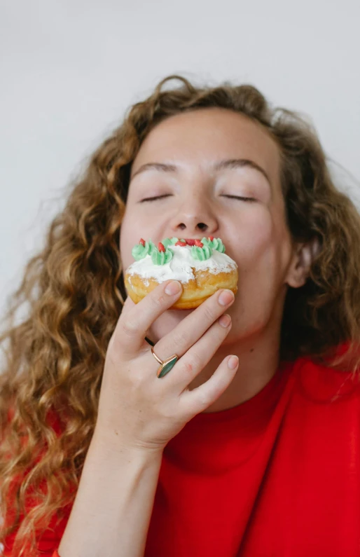 a woman in a red shirt eating a doughnut, a portrait, pexels, whipped cream on top, festive, - 9, a green