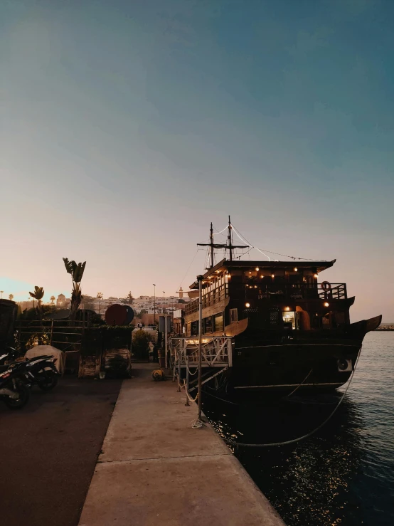 a large boat sitting on top of a body of water, happening, a pirate, evening time, profile image, in a beachfront environment