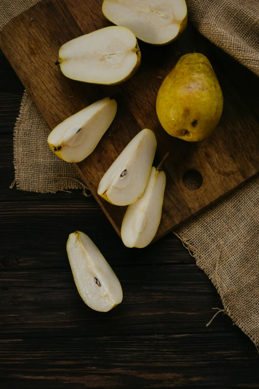 a wooden cutting board topped with sliced pears, by Julia Pishtar, trending on pexels, shades of gold display naturally, thumbnail, whites, full face shot