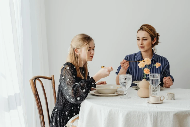 two women sitting at a table eating food, pexels contest winner, kiernan shipka, on a white table, family friendly, sydney sweeney