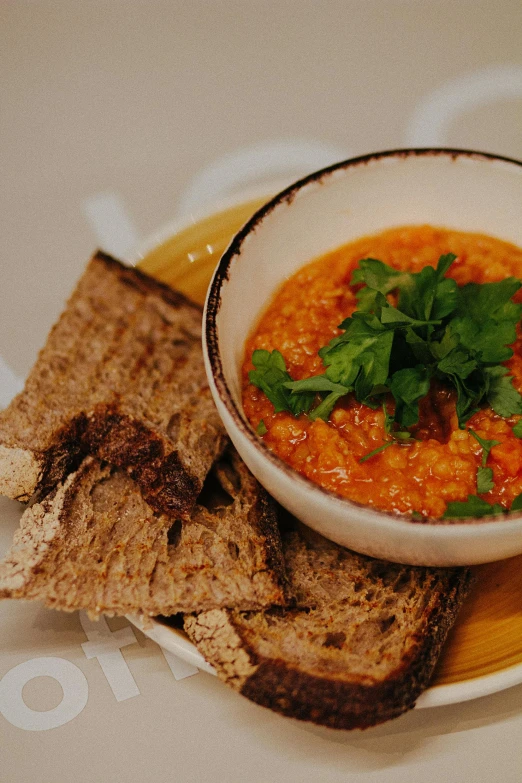 a bowl of soup and some bread on a plate, brightly coloured, finely textured, thumbnail, relish