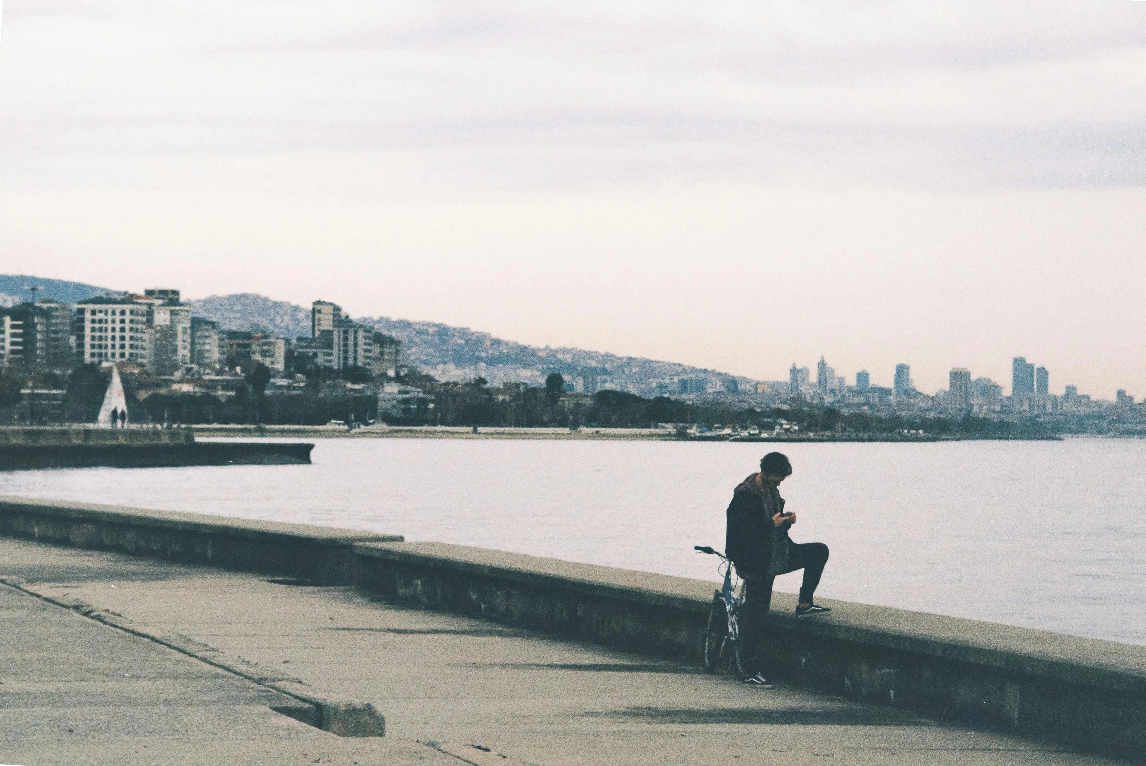 a person sitting on a bench by the water, pexels contest winner, on a sidewalk of vancouver, lone silhouette in the distance, instagram post, feeling miserable