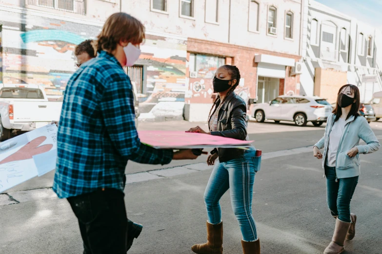 a group of people standing on the side of a road, by Meredith Dillman, pexels contest winner, graffiti, delivering parsel box, presenting a large pizza, wearing facemask, at a city street