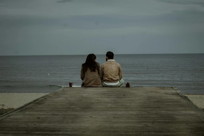 a man and a woman sitting on a pier looking out at the ocean, a picture, pexels contest winner, romanticism, brown, grey, unfinished, calmly conversing 8k