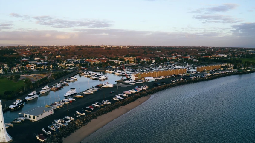 a harbor filled with lots of boats next to a lighthouse, pexels contest winner, happening, caulfield, aerial footage, bored ape yacht club, sunset beach