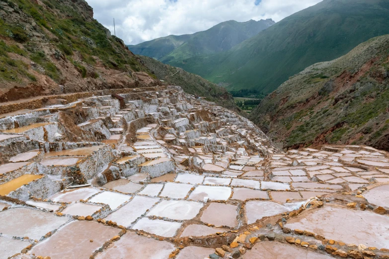 a stone walkway in the mountains with mountains in the background, a mosaic, by Julia Pishtar, trending on unsplash, peru, white and gold robes, cubic minerals, pink water in a large bath