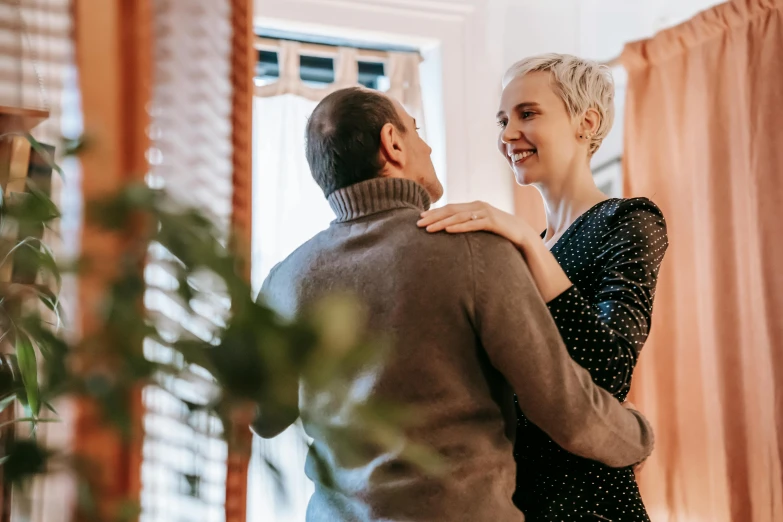 a woman standing next to a man in a living room, by Carey Morris, pexels contest winner, renaissance, flirting smiling, girl with short white hair, couple dancing, leaning on door