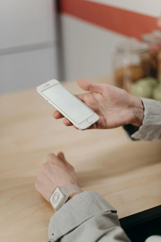 a close up of a person holding a cell phone, a picture, sitting on a table, presenting wares, white sleeves, uploaded