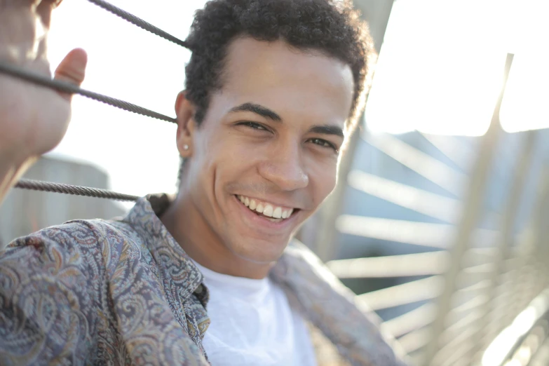 a close up of a person holding a tie, by Jacob Toorenvliet, brown skin man with a giant grin, curly and short top hair, relaxing and smiling at camera, mixed race