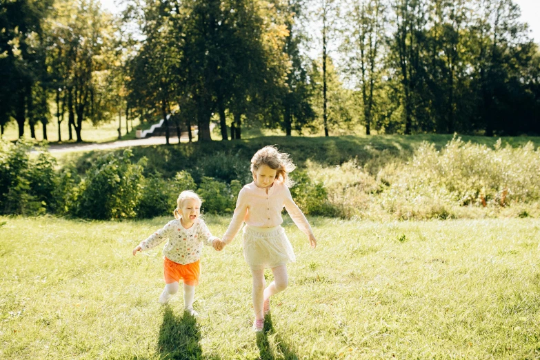 a couple of kids running across a lush green field, by Jaakko Mattila, pexels, sunny day in a park, sisters, midsommar - t, small