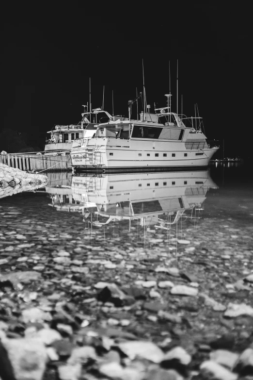 a black and white photo of a boat in the water, by Jim Nelson, crystal clear neon water, some reflexions, antartic night, detailed medium format photo