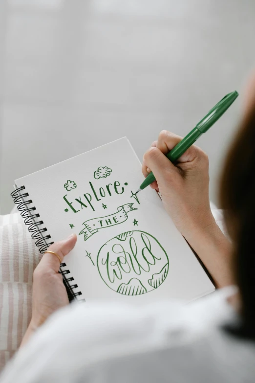 a woman writing on a notebook with a green pen, inspired by JoWOnder, explorer sketch, style lettering, childs drawing, whiteboard