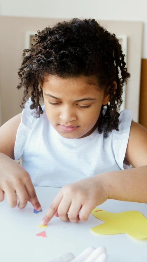a little girl that is sitting at a table, pexels, process art, african american young woman, from reading to playing games, loosely cropped, slide show