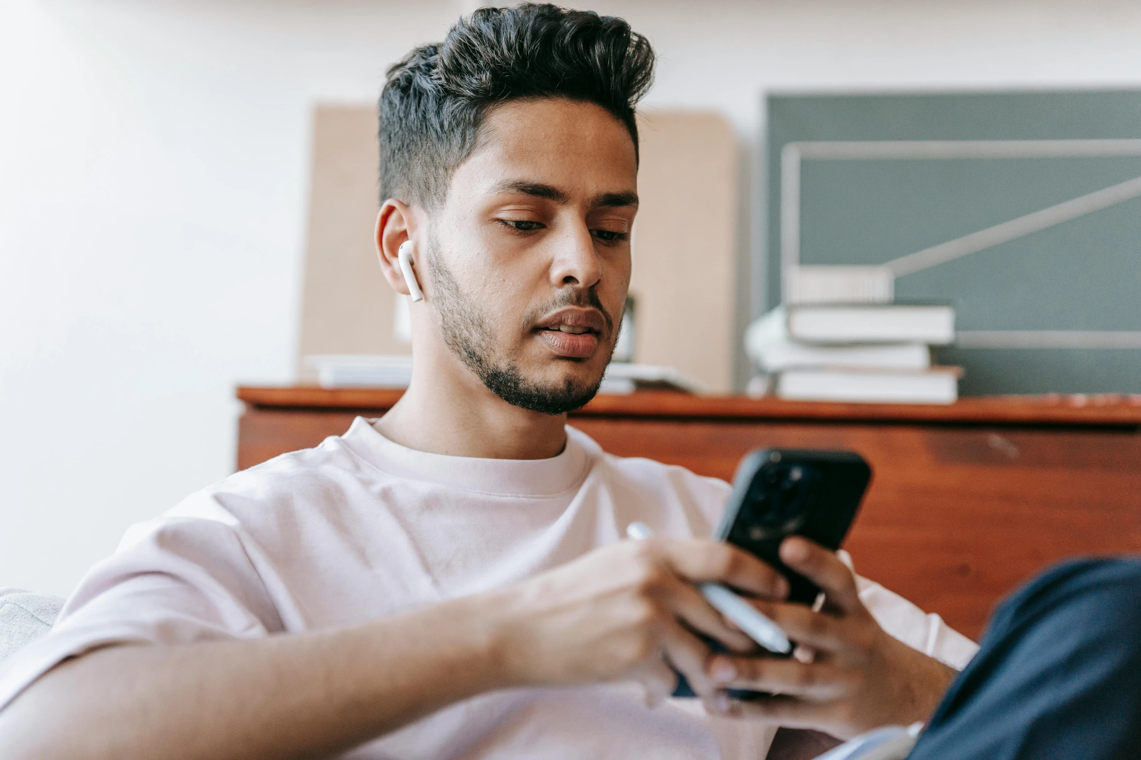 a man sitting on a couch looking at his cell phone, trending on pexels, avatar image, lgbtq, wearing gaming headset, sitting on edge of bed