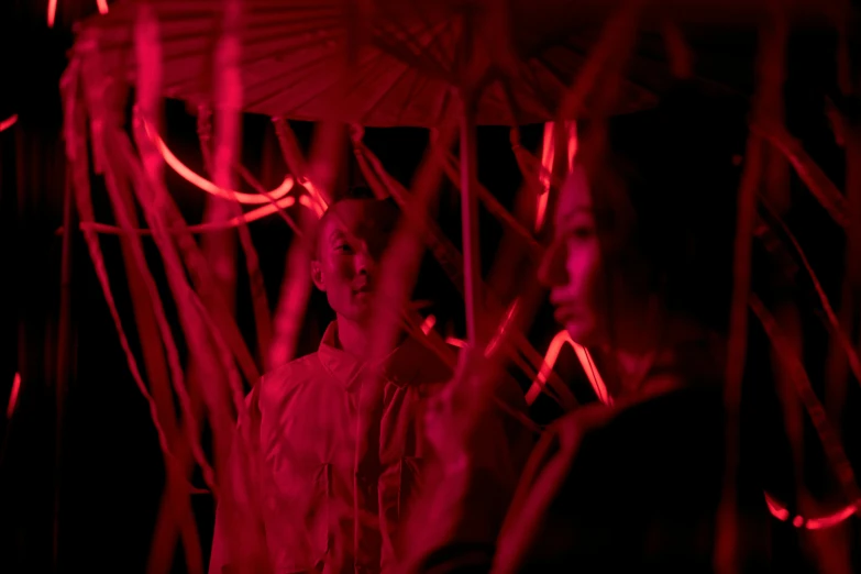 a woman holding an umbrella in a dark room, inspired by Chiharu Shiota, conceptual art, medium shot of two characters, red lasers, red grass, neon jungle