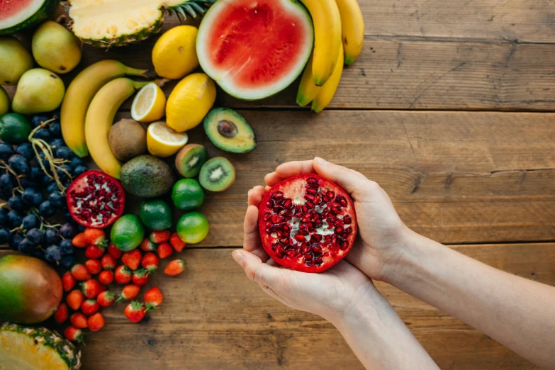 a person holding a pomegranate in their hands, a still life, trending on pexels, gestation inside a watermelon, avatar image, ingredients on the table, multicoloured