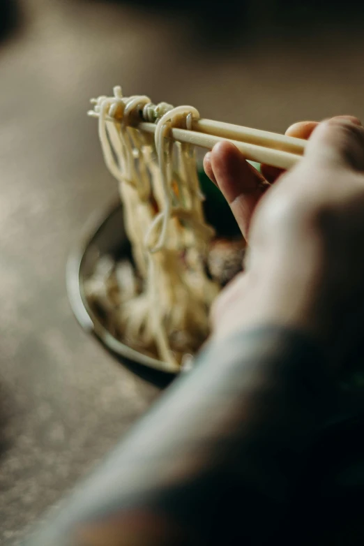 a person holding chopsticks over a bowl of noodles, unsplash, process art, neck zoomed in, hanging, local close up, plating