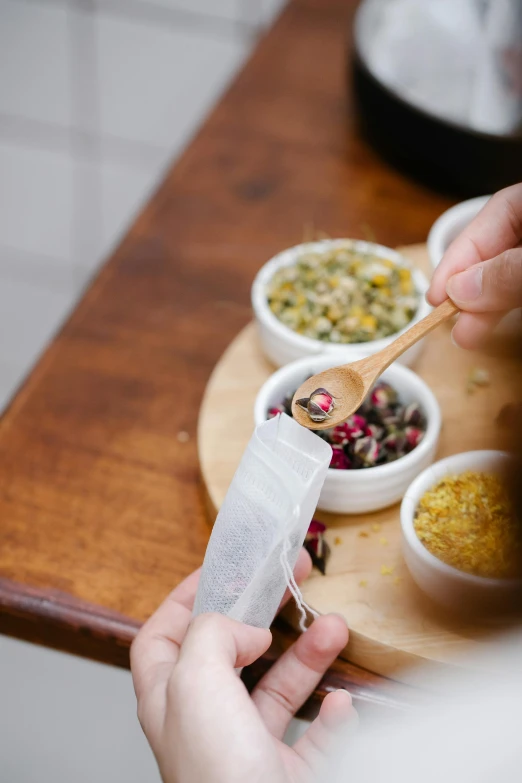 a person holding a wooden spoon over a bowl of food, botanicals, teapots, candy treatments, hazy