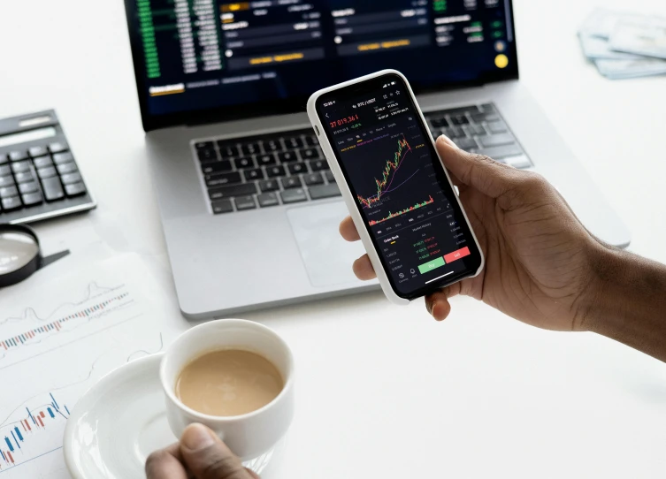 a person holding a cell phone next to a cup of coffee, trading stocks, avatar image, thumbnail, schools