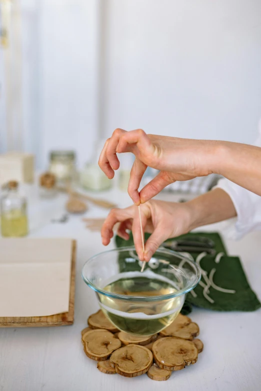 a person sitting at a table with a bowl of food, process art, candle dripping white wax, cooking oil, professional product shot, curved blades on each hand