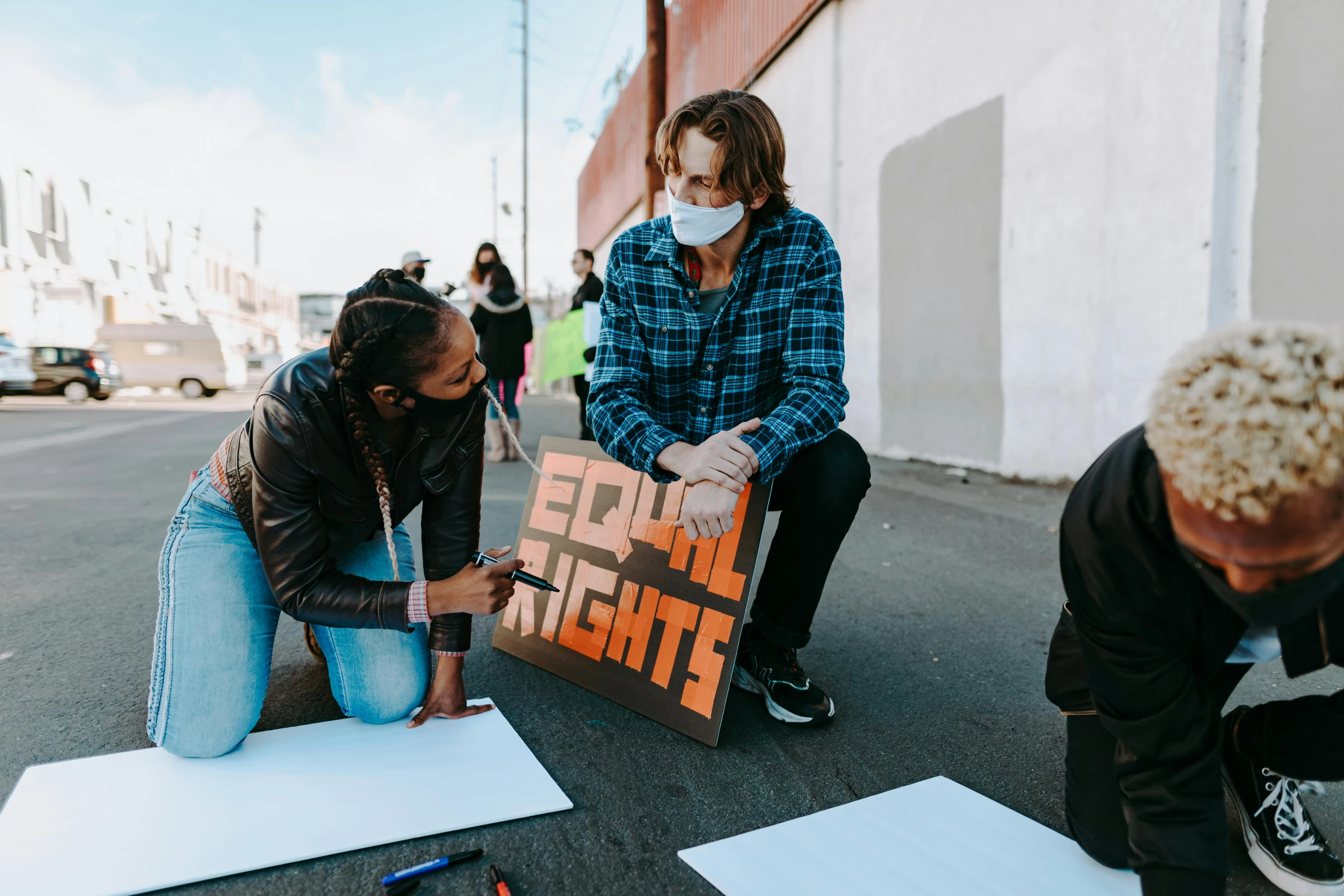 a group of people standing on top of a street, pexels contest winner, sots art, woman his holding a sign, trans rights, worksafe. instagram photo, lachlan bailey