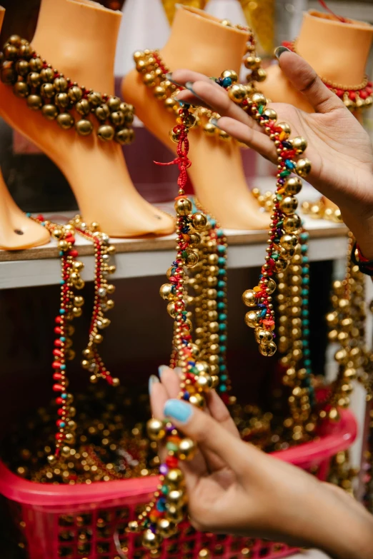 a woman is putting beads on a mannequin, trending on unsplash, renaissance, jester shoes, gold and red metal, brazil, in louisiana