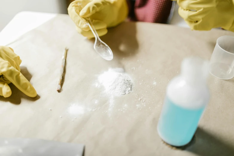 a person in yellow gloves is cleaning a table, inspired by Elsa Bleda, trending on pexels, cocaine, with a lab coat, magic powder, crime scene photo