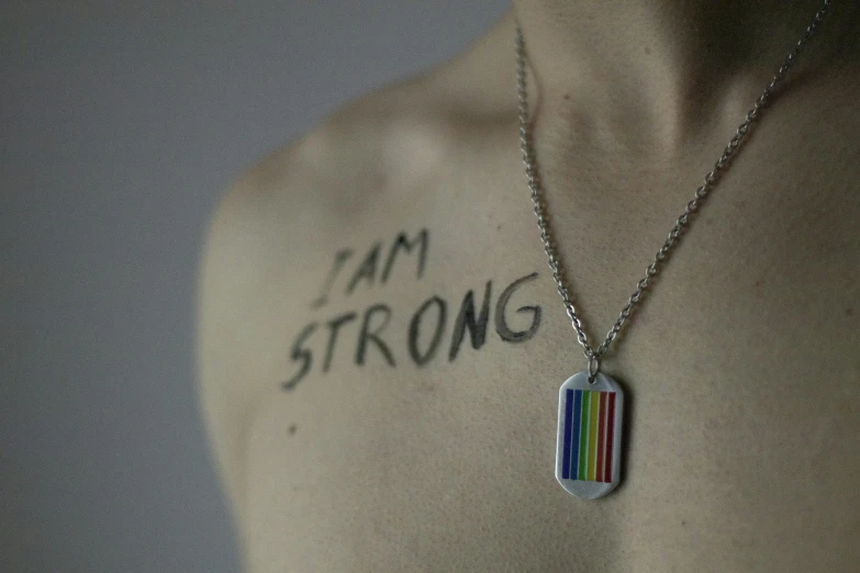 a man with the word i am strong on his chest, by Matija Jama, rainbows, necklace on display, anna nikonova, photographed for reuters