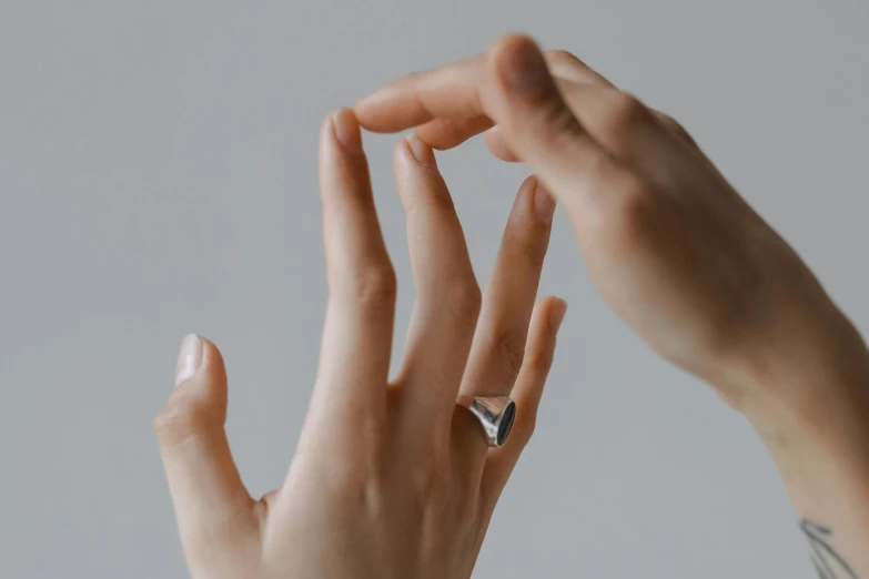 a close up of a person's hand with a ring on it, trending on pexels, hyperrealism, on grey background, holding a pudica pose, animation, silver，ivory