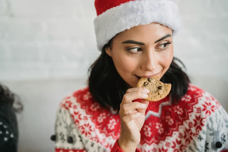 a woman in a santa hat eating a cookie, by Julia Pishtar, pexels, looking to the right, avatar image, lifestyle, uk