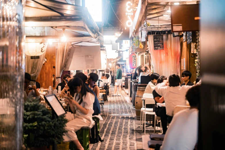 a group of people sitting at tables in a restaurant, by Julia Pishtar, unsplash, tokyo alleyway, in chippendale sydney, summer evening, conde nast traveler photo