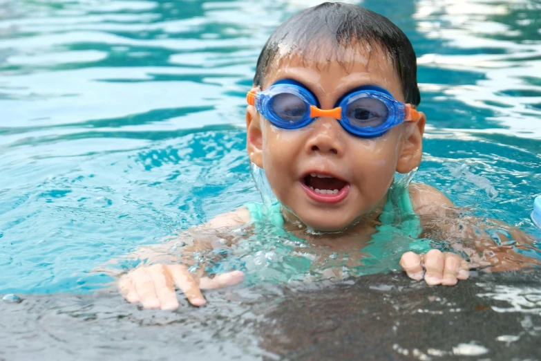 a young boy wearing goggles swimming in a pool, emerging from the water, all overly excited, gofl course and swimming, thumbnail