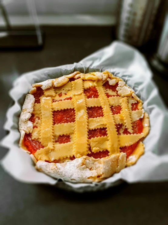 a pie sitting on top of a piece of paper, red and yellow, lattice, covered in white flour, singapore