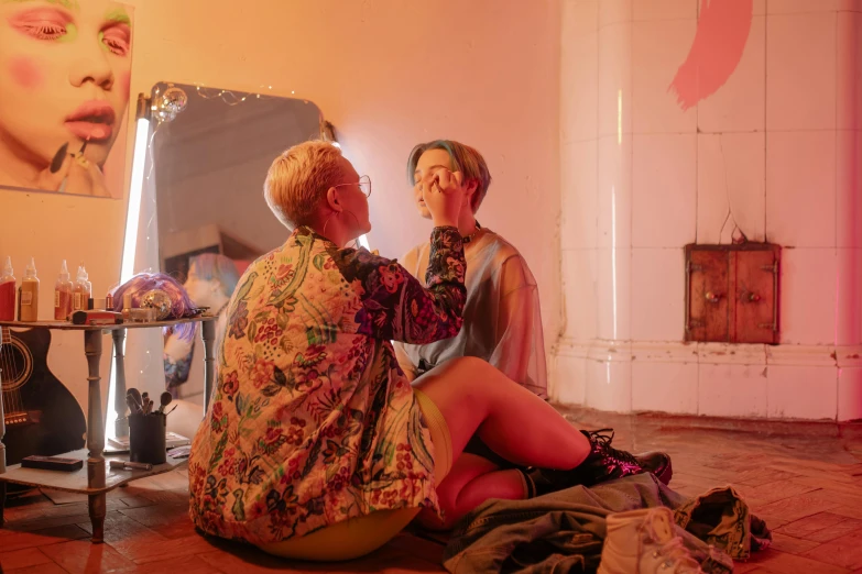 a woman sitting on the floor in front of a mirror, by Emily Mason, huge earrings and queer make up, kda and sam yang, putting makeup on, lachlan bailey