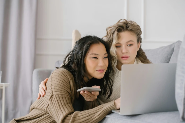 two women sitting on a couch looking at a laptop, trending on pexels, avatar image, movies, asian women, one blonde and one brunette