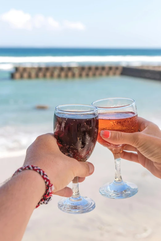 two people toasting with wine glasses on the beach, by Carey Morris, pexels contest winner, reunion island, mauve and cinnabar and cyan, bondi beach in the background, beer