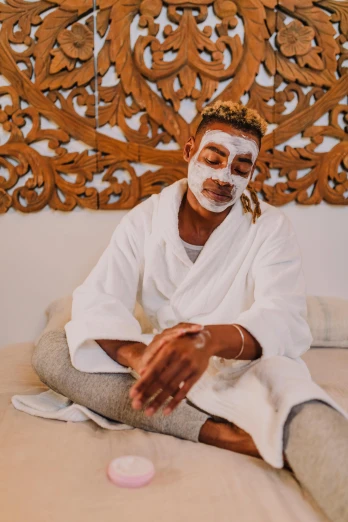 a man in a white robe sitting on a bed, trending on pexels, renaissance, day - glow facepaint, african mask, skincare, with textured hair and skin