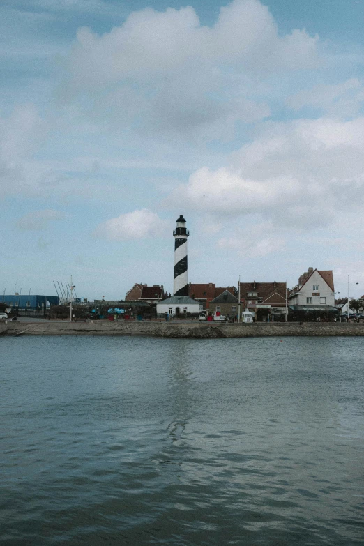 a large body of water with a light house in the background, by Jan Davidsz de Hem, unsplash, fishing village, square, low quality photo, taken in the mid 2000s