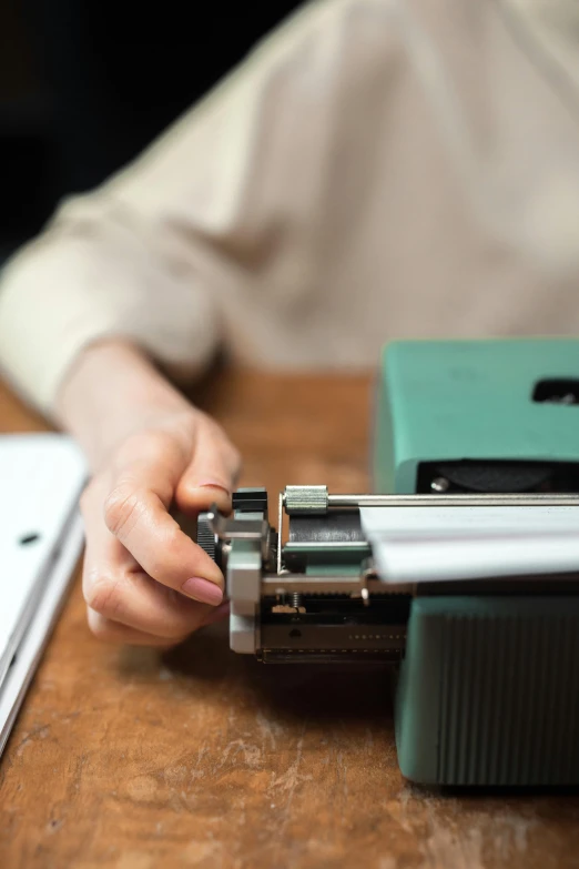 a person sitting at a table with a typewriter, an album cover, unsplash, private press, professional gunsmithing, closeup of arms, teaching, high quality photo