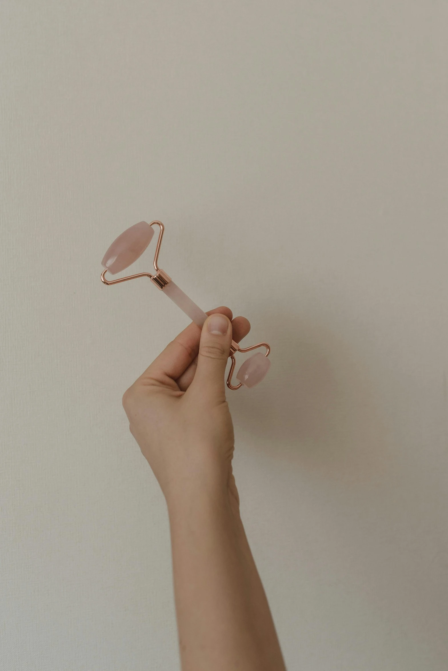 a person holding a pink object in their hand, by Emma Andijewska, trending on pexels, small square glasses, speculum, twirly, light tan