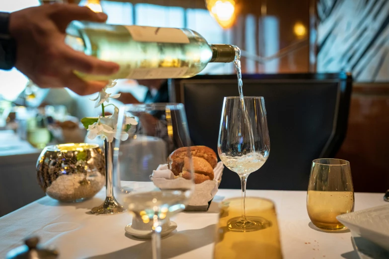 a person pouring wine into a glass on a table, michelin restaurant, fan favorite, at the waterside, extra detail