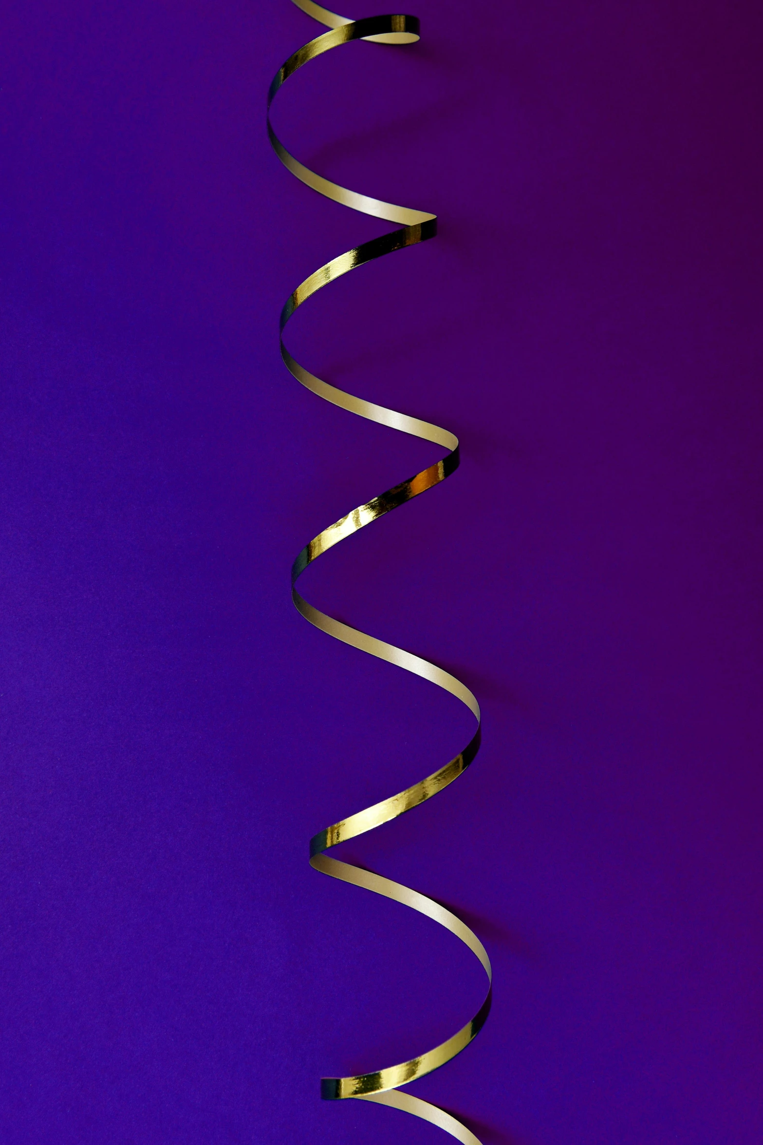 a spiral of gold foil against a purple background, by Doug Ohlson, ribbons, ((purple)), minimalist photorealist, medium long shot