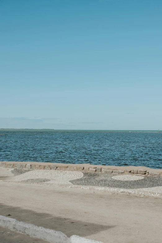 a man riding a skateboard on top of a sandy beach, by Nina Hamnett, trending on unsplash, les nabis, the harbour at stromness orkney, panorama distant view, blue cobblestones, tallinn