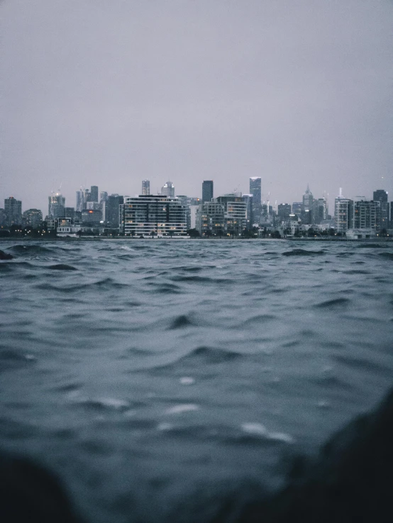 a body of water with a city in the background, by Ryan Pancoast, pexels contest winner, heavy rainy, wavy water, lachlan bailey, leaked photo