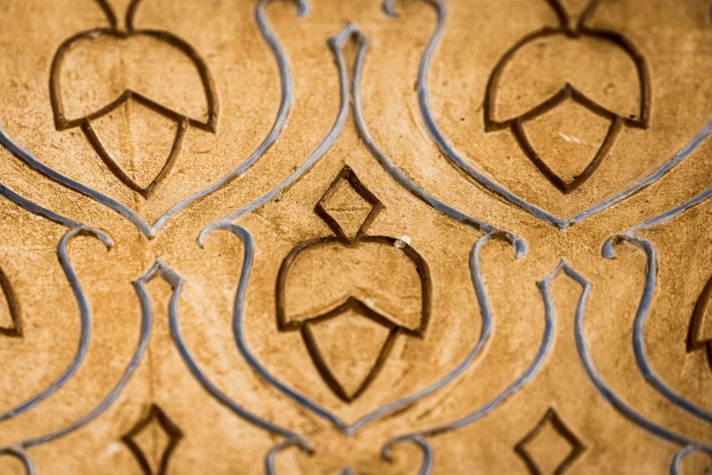 a close up of a pattern on a wall, inspired by Riad Beyrouti, trending on unsplash, arts and crafts movement, brown and gold, cartouche, embossed, intaglio style