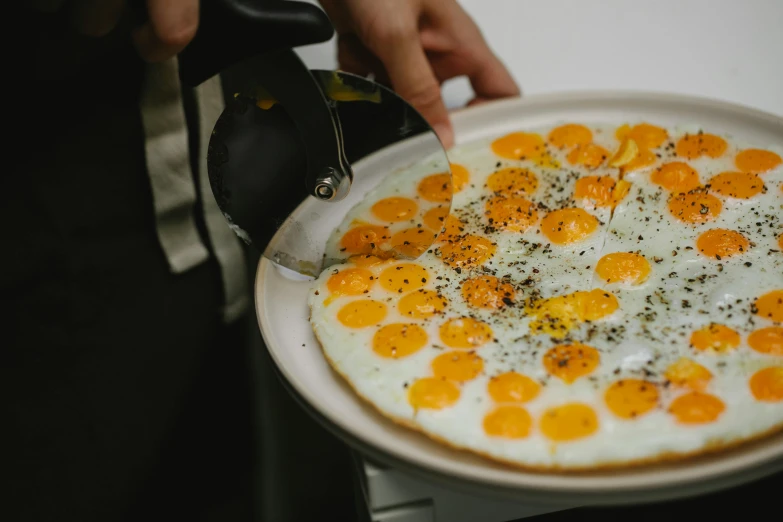 a white plate topped with eggs on top of a stove, inspired by Géza Dósa, private press, holding pizza, raw egg yolks, monocle, high quality product photo