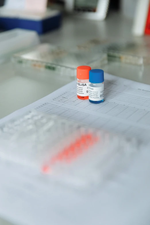 two vials sitting on top of a piece of paper, diagnostics, on a white table, in a research facility, thumbnail